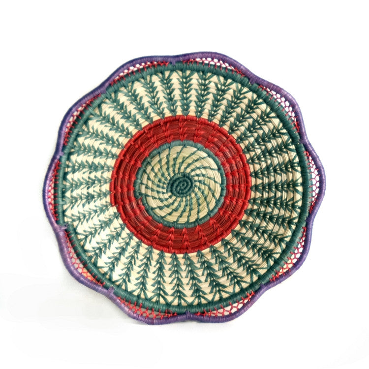 Josefina basket is a fair trade delicately handwoven basket made of native grass and pine needles with colorful raffia accents and a scalloped rim, created and designed by the women of Mayan Hands El Triunfo cooperative.